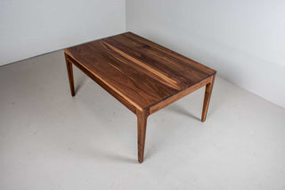 minimalist walnut dining table with a custom parsons base that is flush with the table top and has tapered legs