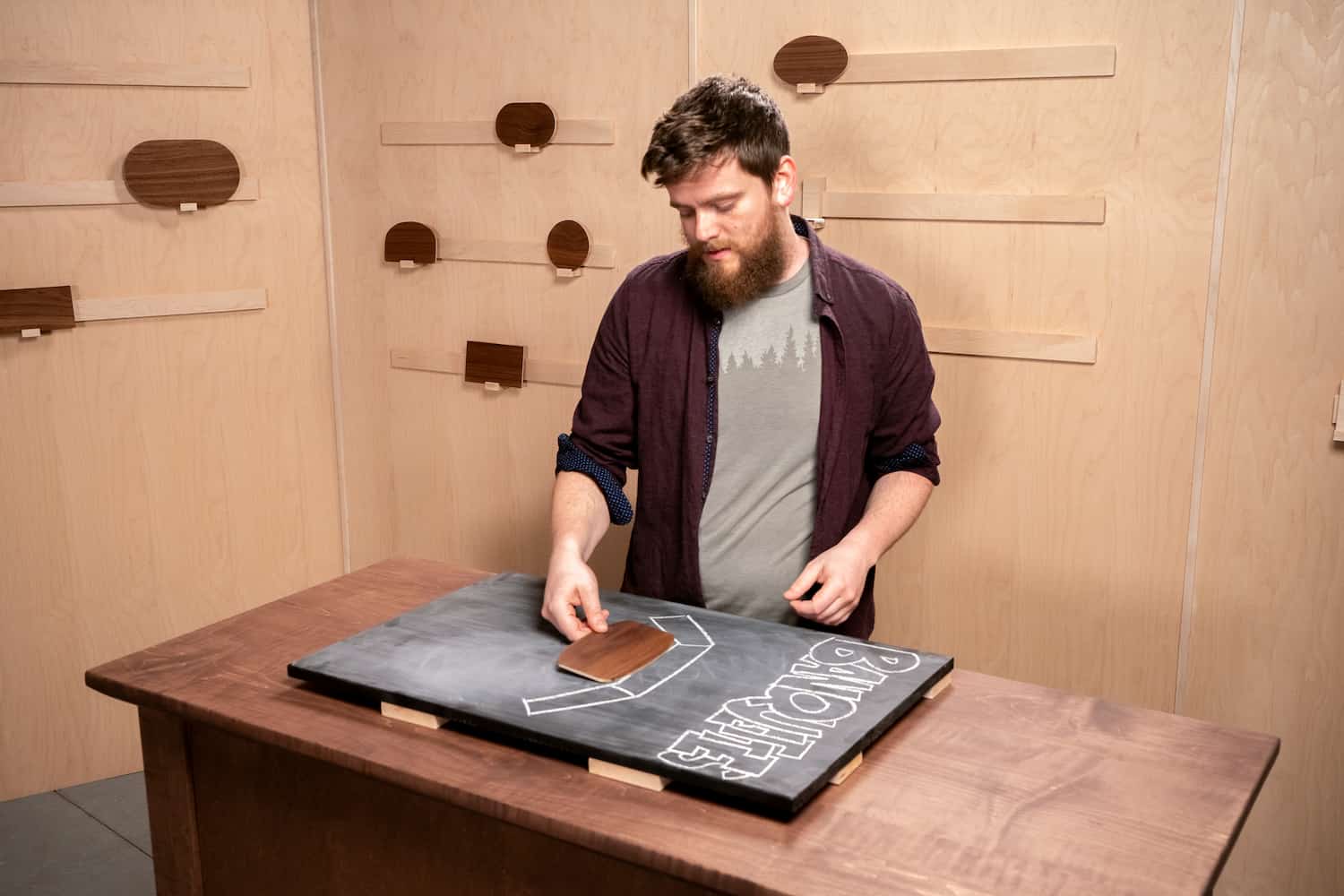 Josh standing at a table with a blackboard on it and model table tops behind him