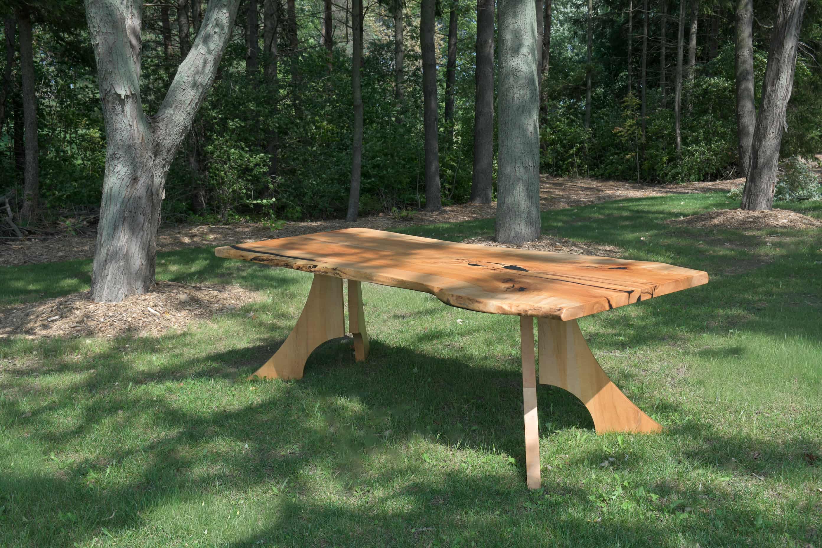 A photo of a book matched maple dining table outdoors