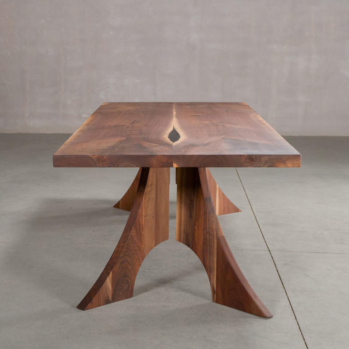 end view of a bookmatch Walnut table 40” wide x 108” long, finished in Pure D on Alta legs