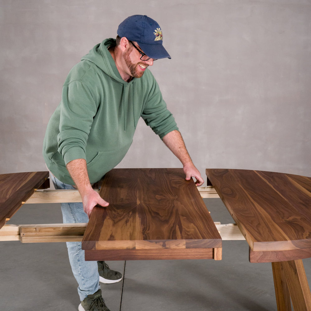 person adding a leaf to a round extendable table