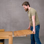 person adding a leaf to the end of an extendable Oak Parsons table 36” wide x 68” long, finished in Pure D on Estling base