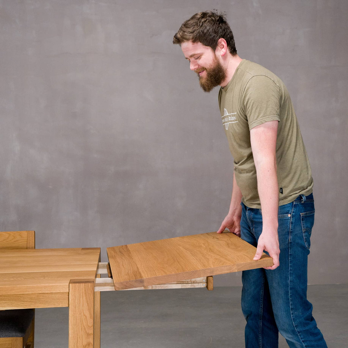 person adding a leaf to the end of an extendable Oak Parsons table 36” wide x 68” long, finished in Pure D on Estling base