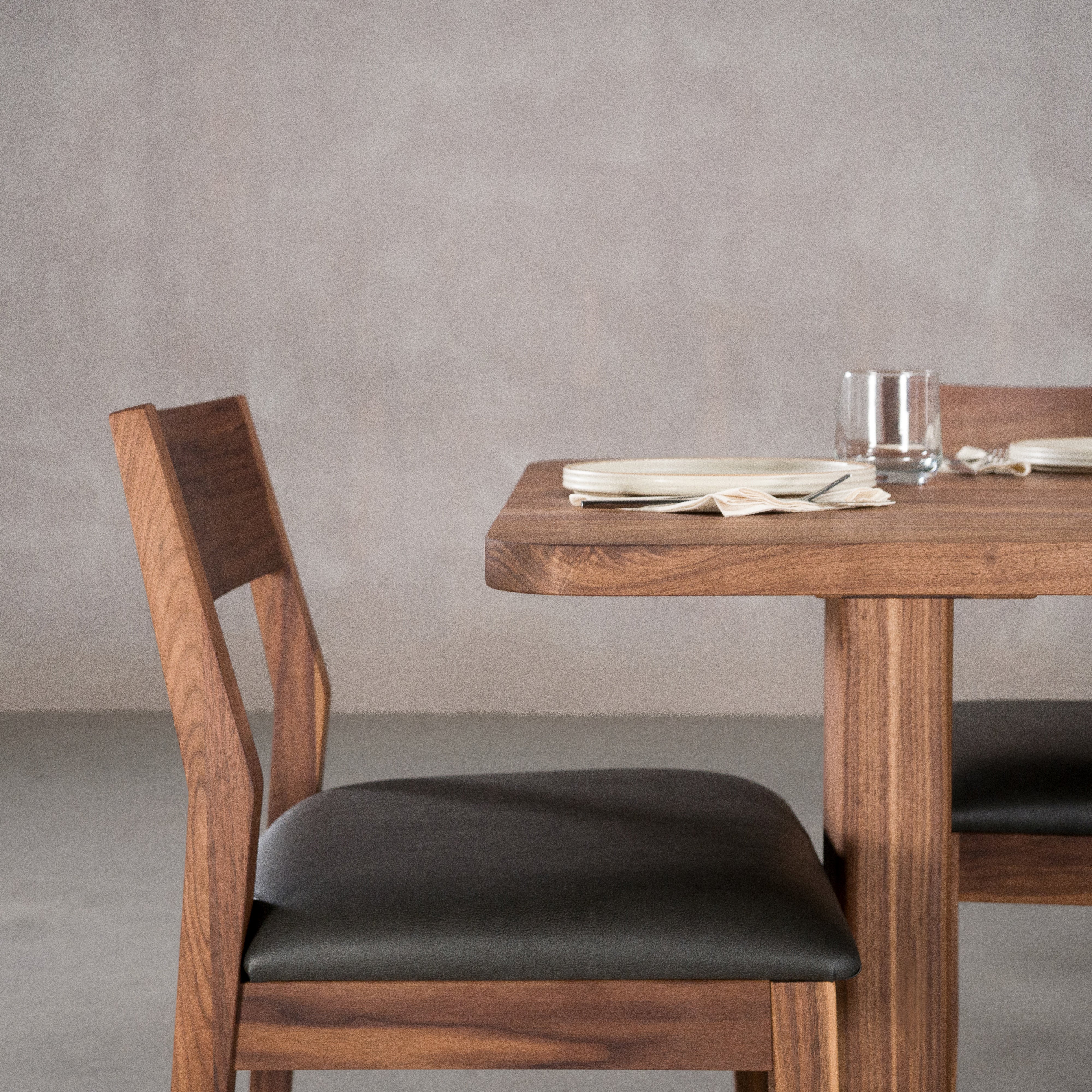 chair at end of a rectangle Walnut table 36” wide x 72” long, finished in Pure D on Tobin trestle base