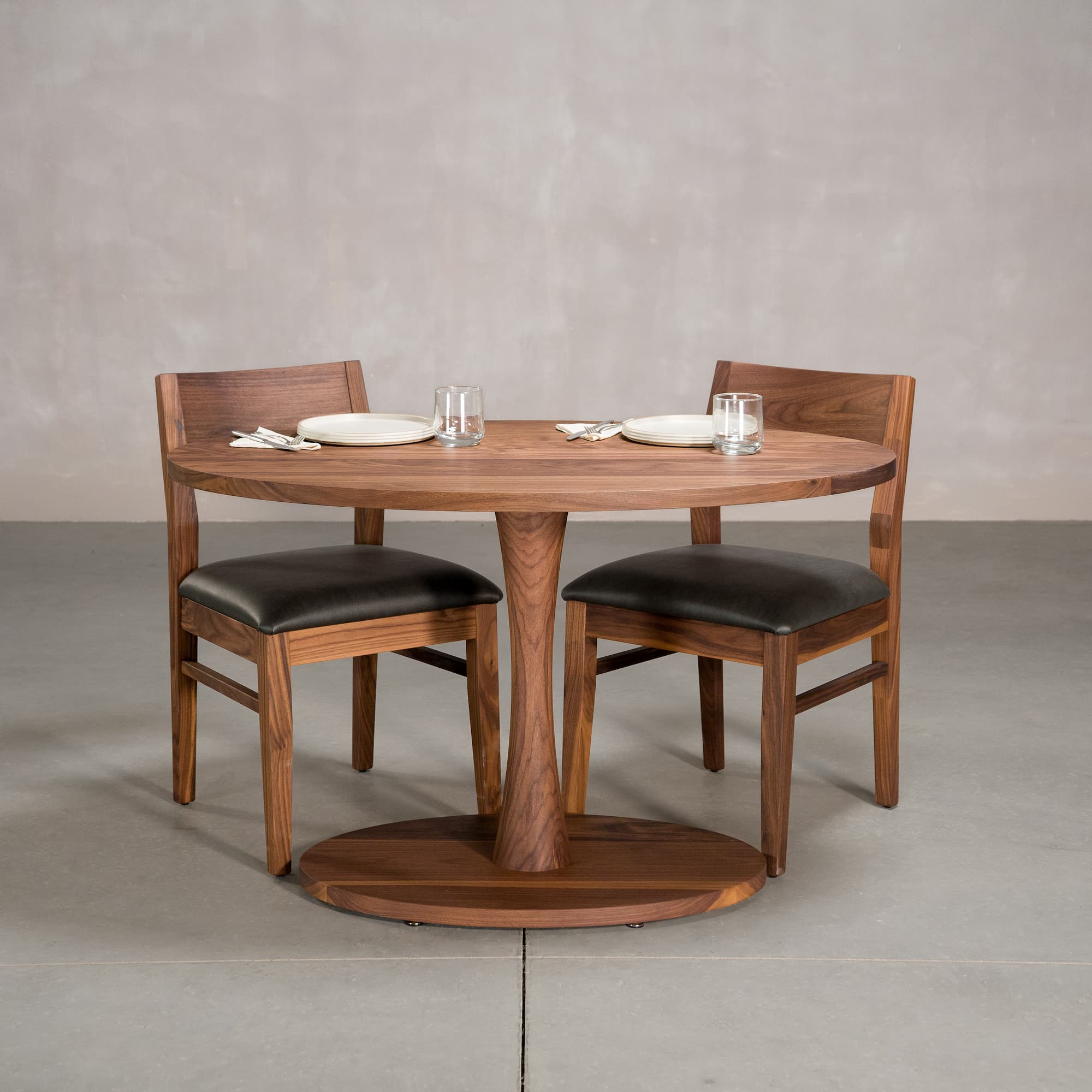 elliptical Walnut table 30” wide x 48” long, finished in Pure D on a Jennings pedestal base, shown with Aubrey chairs