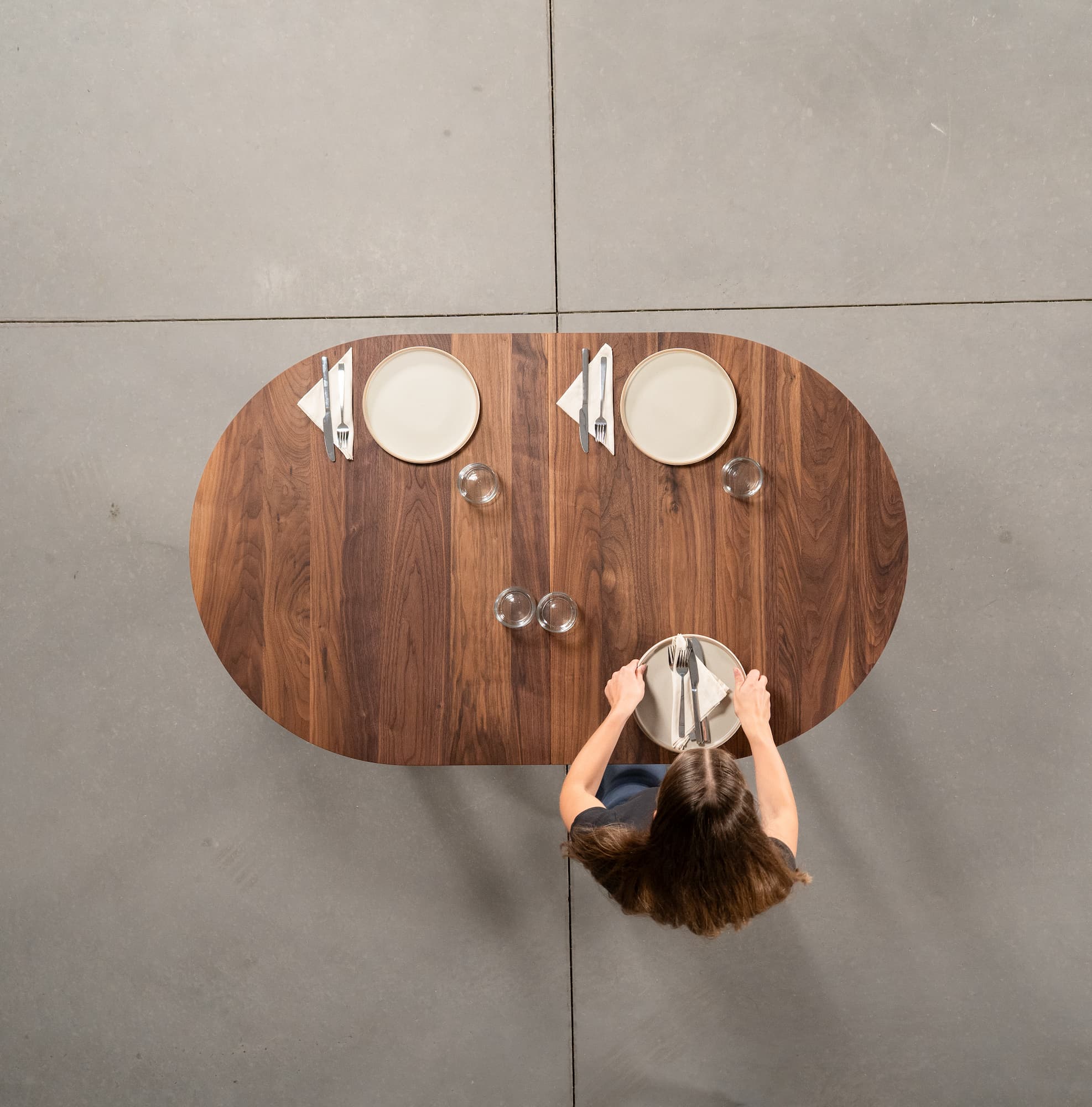 person setting an oval extendable Walnut table 36” wide x 60” long, finished in Pure D
