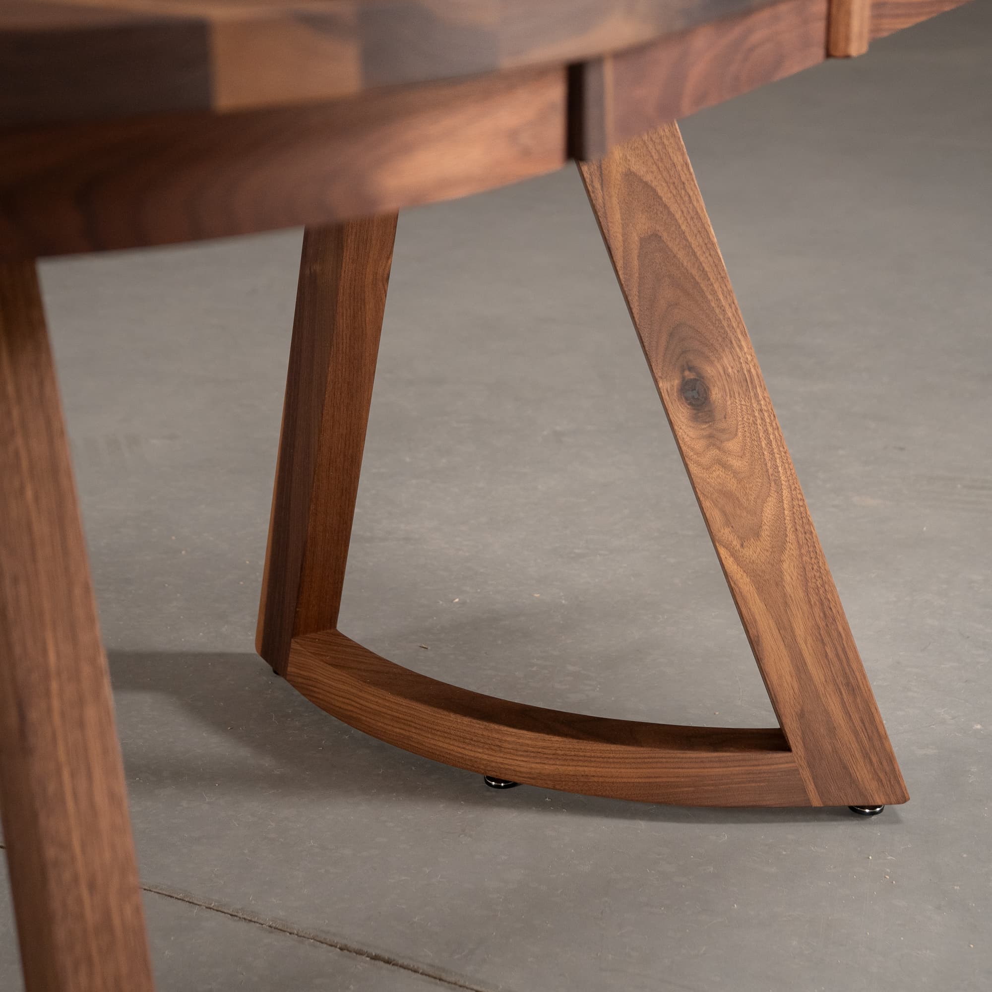 the curve of Chesbro legs on an oval extendable Walnut table finished in Pure D 