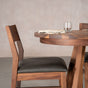 an Aubrey chair placed at the end of an oval extendable Walnut table finished in Pure D on Chesbro legs