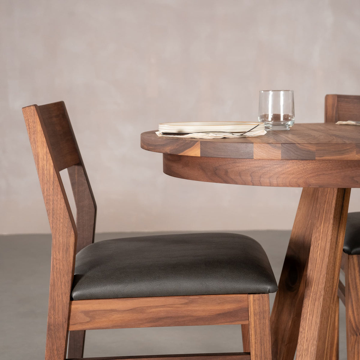 an Aubrey chair placed at the end of an oval extendable Walnut table finished in Pure D on Chesbro legs
