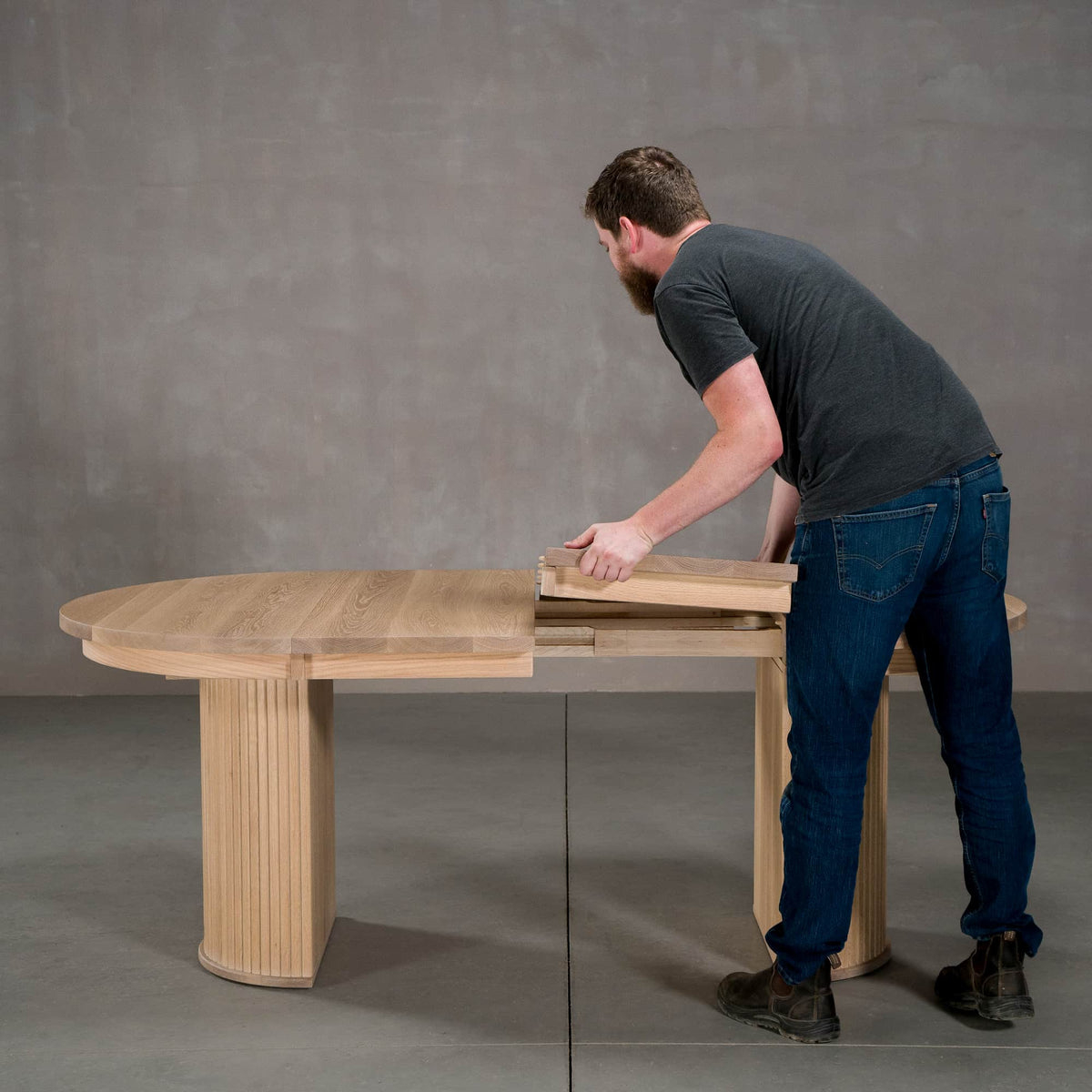 person adding a leaf to a round extendable White Oak table 42” wide x 42” long, finished in Clear D on Split Como base
