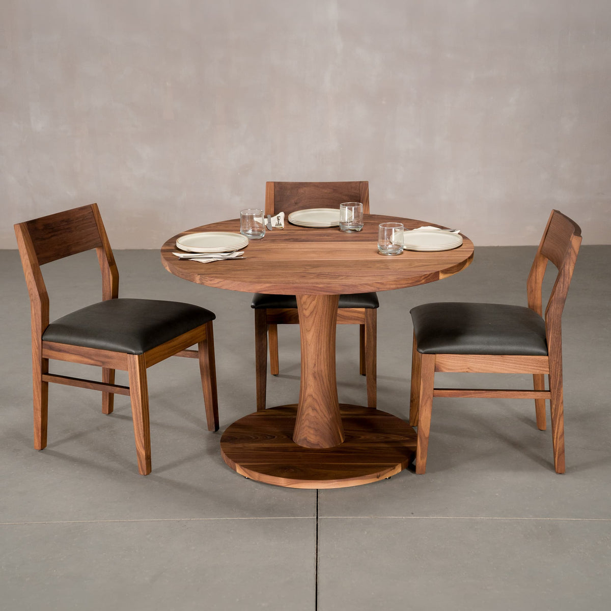 round Walnut table 42” wide x 42” long, finished in Pure D on Jennings pedestal base shown with Aubrey chairs

