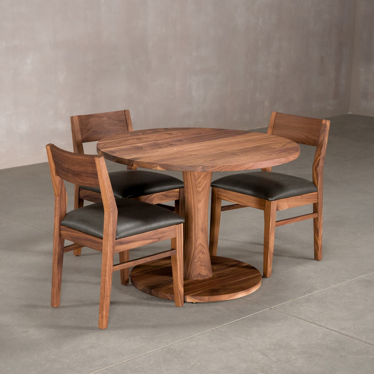 round Walnut table 42” wide x 42” long, finished in Pure D on Jennings pedestal base; shown with Aubrey chairs