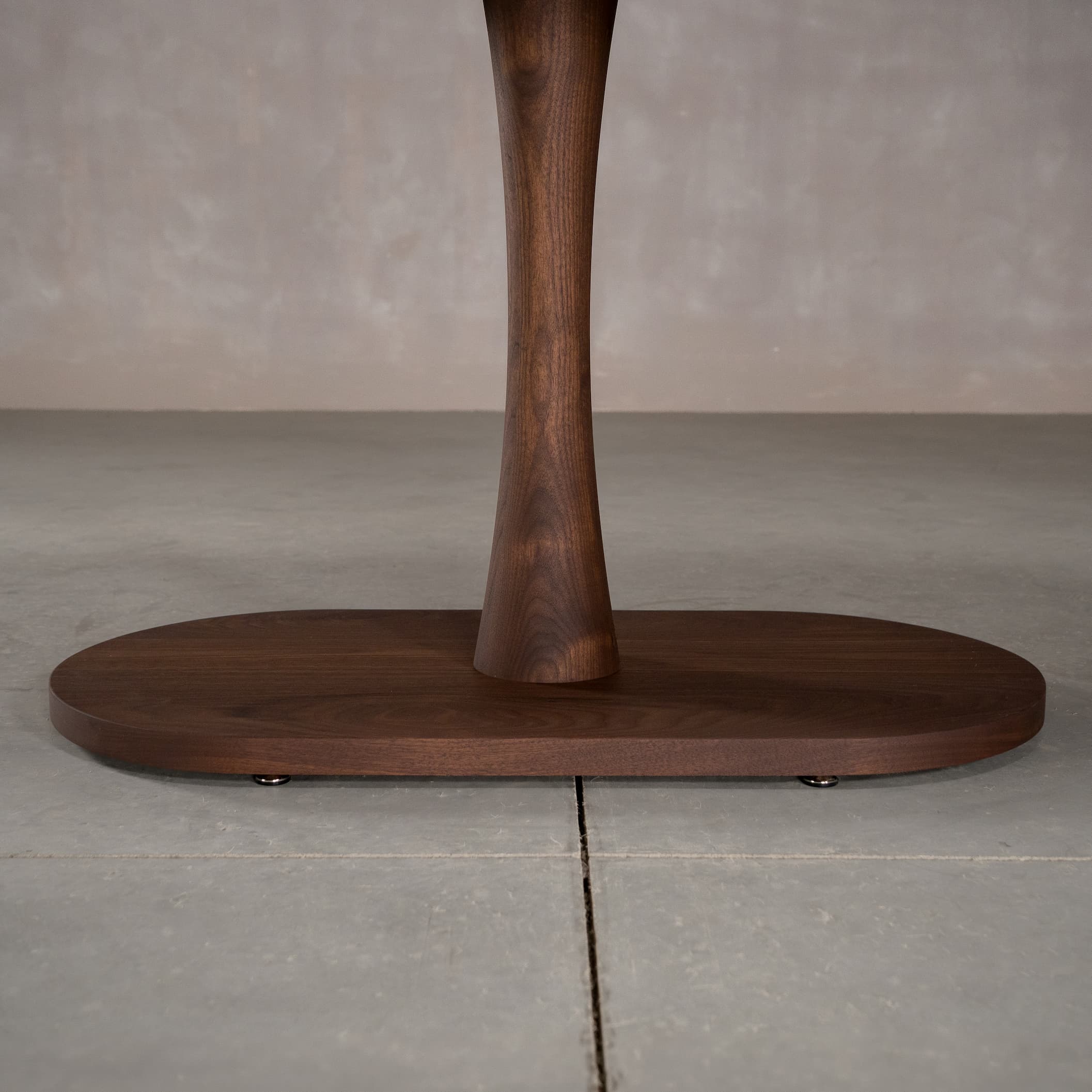 close up of the Jennings pedestal base on an oval Walnut table finished in Cortado D