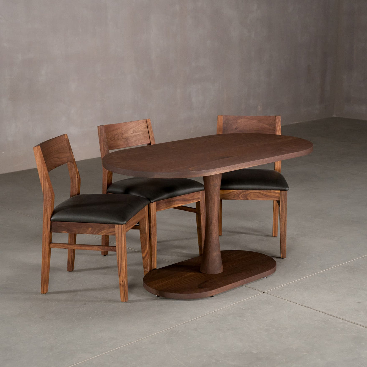 oval Walnut table 29” wide x 55” long, finished in Cortado D on a Jennings pedestal base, shown with Aubrey chairs