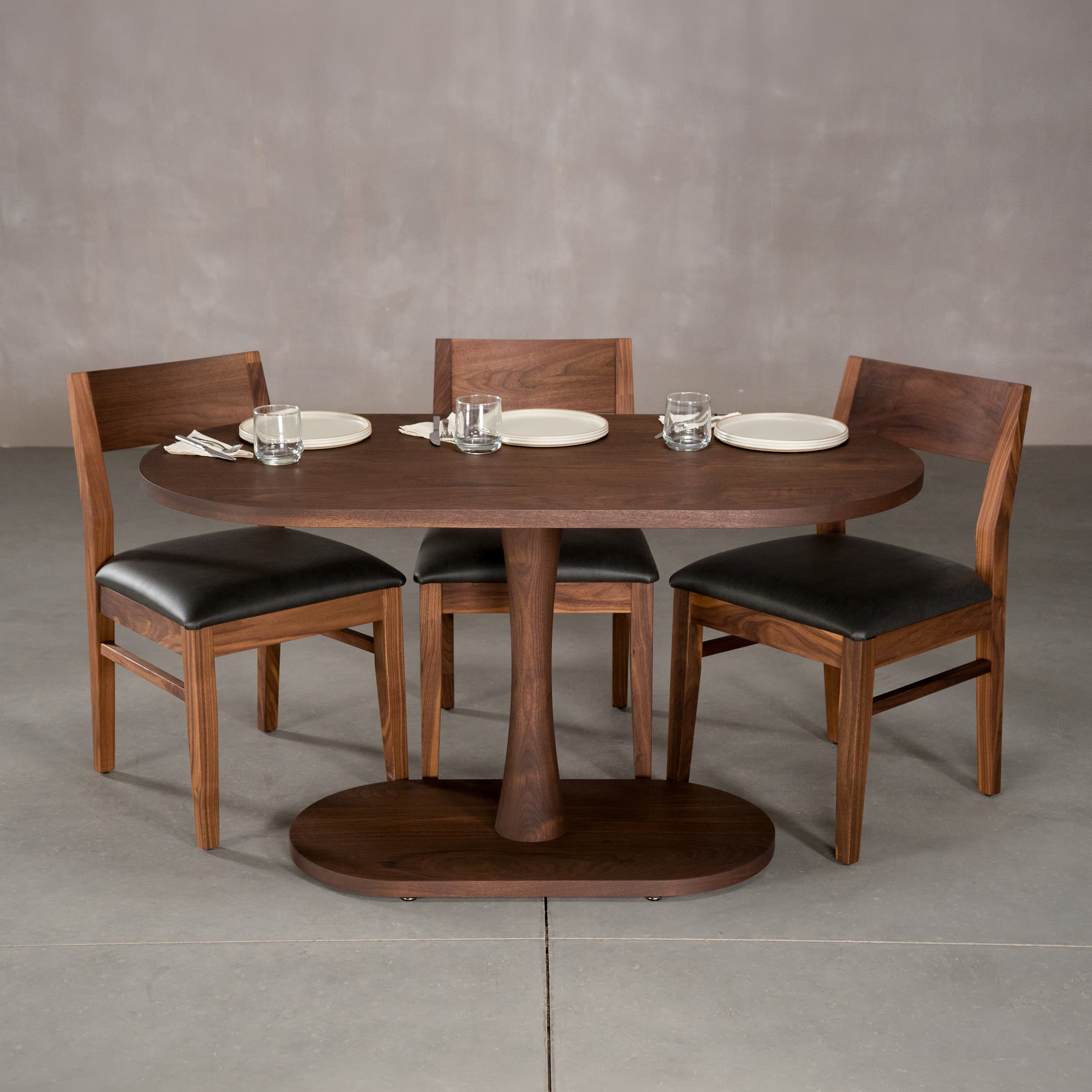 oval Walnut table 29” wide x 55” long, finished in Cortado D on a Jennings pedestal base, shown with Aubrey chairs