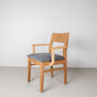 Oak dining chair with arms finished in Pure D shown with a gray fabric seat
