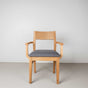 Oak dining chair with arms finished in Pure D shown with a gray fabric seat