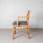 Oak dining chair with arms finished in Pure D shown with a gray fabric seat