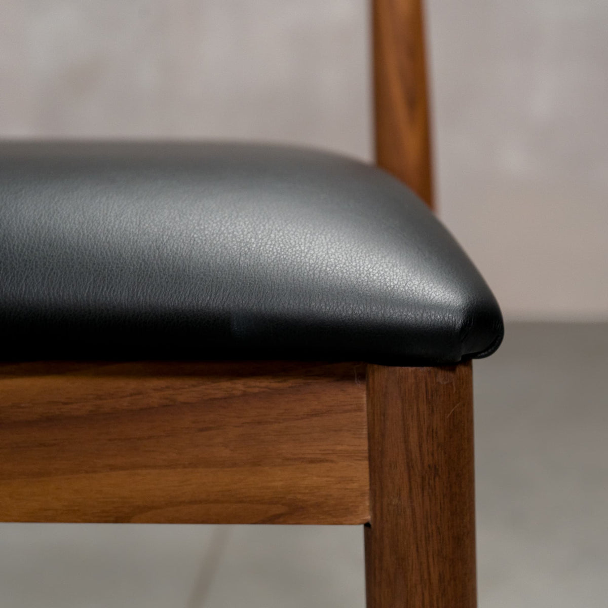seat detail of a midcentury modern Walnut dining chair with an Onyx Faux Leather seat