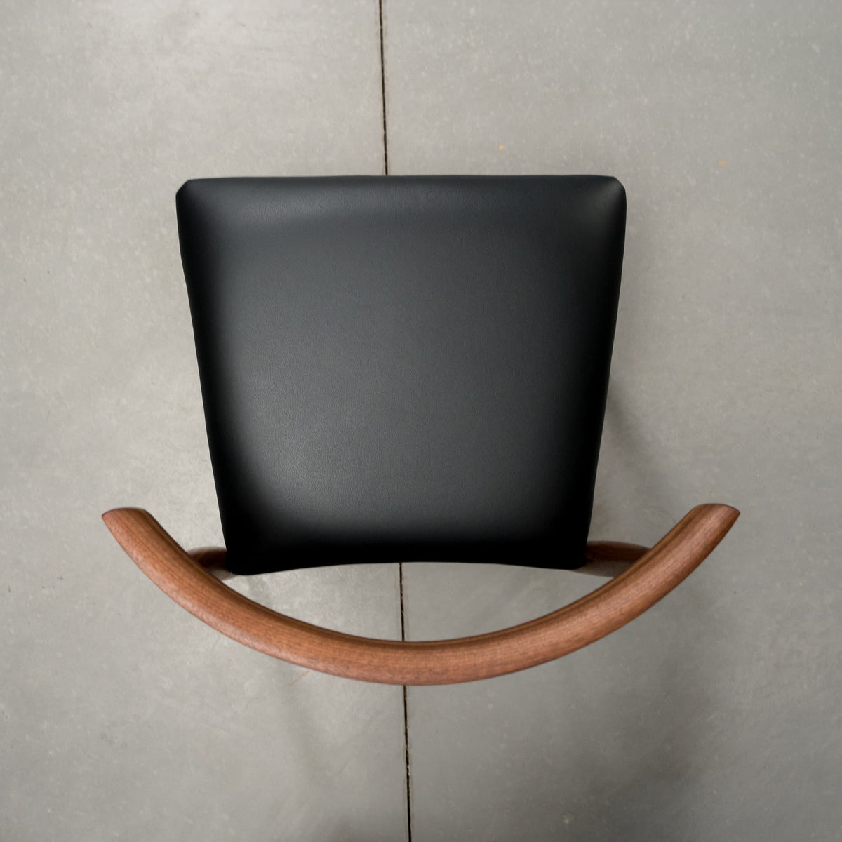 overhead view of a midcentury modern Walnut dining chair with an Onyx Faux Leather seat