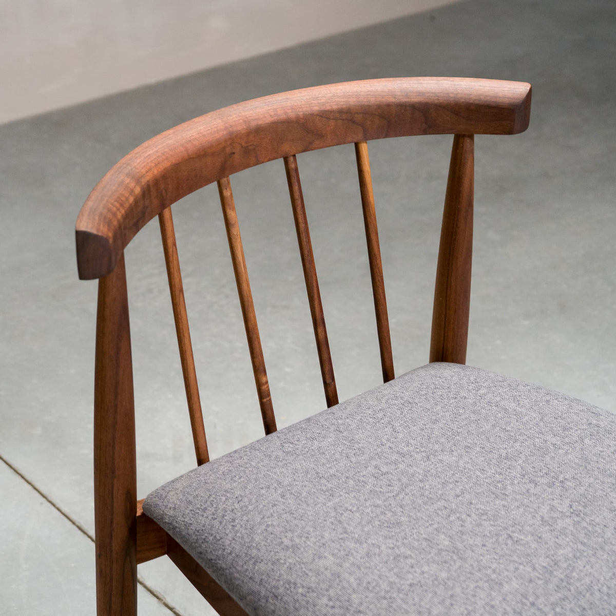 back detail of a midcentury modern Walnut dining chair with back spindles and Graphite fabric seat