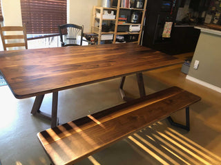walnut table and bench with rounded corners on steel chevron legs