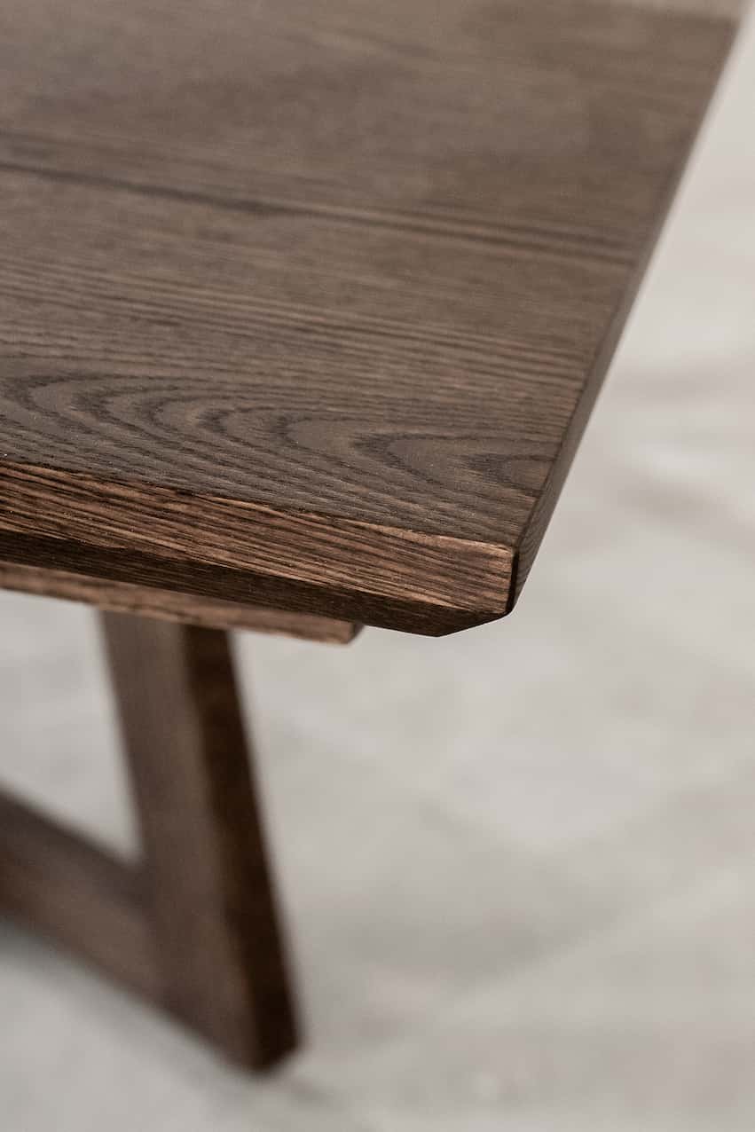 Close-up of a red oak wood table corner on a light background