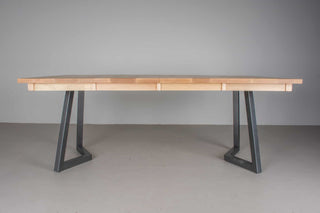 side profile of Scandinavian dining table with light colored square top at extending size of 42x76 on black steel chevron legs