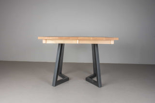 side profile of Scandinavian dining table with light colored square top  on black steel chevron legs