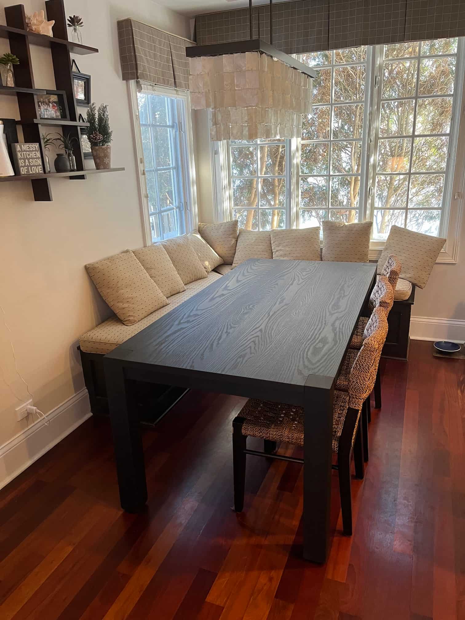 oak table in black paired with beige upholstered bench in front of a window in a kitchen