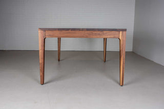 minimalist walnut dining table with a custom parsons base that is flush with the table top and has tapered legs