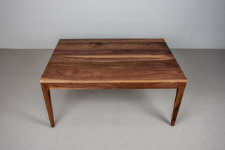 minimalist walnut dining table with a custom parsons base that is flush with the table top and has tapered legs