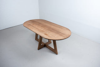 oval maple table finished in coconut on cross pedestal base