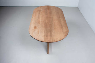 oval maple table finished in coconut on cross pedestal base