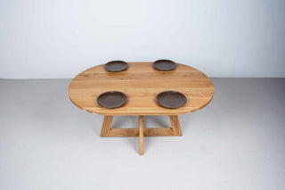 oval white oak dining table on single cross pedestal base