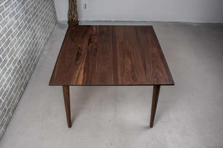square blackened walnut extendable table on mid century parsons base