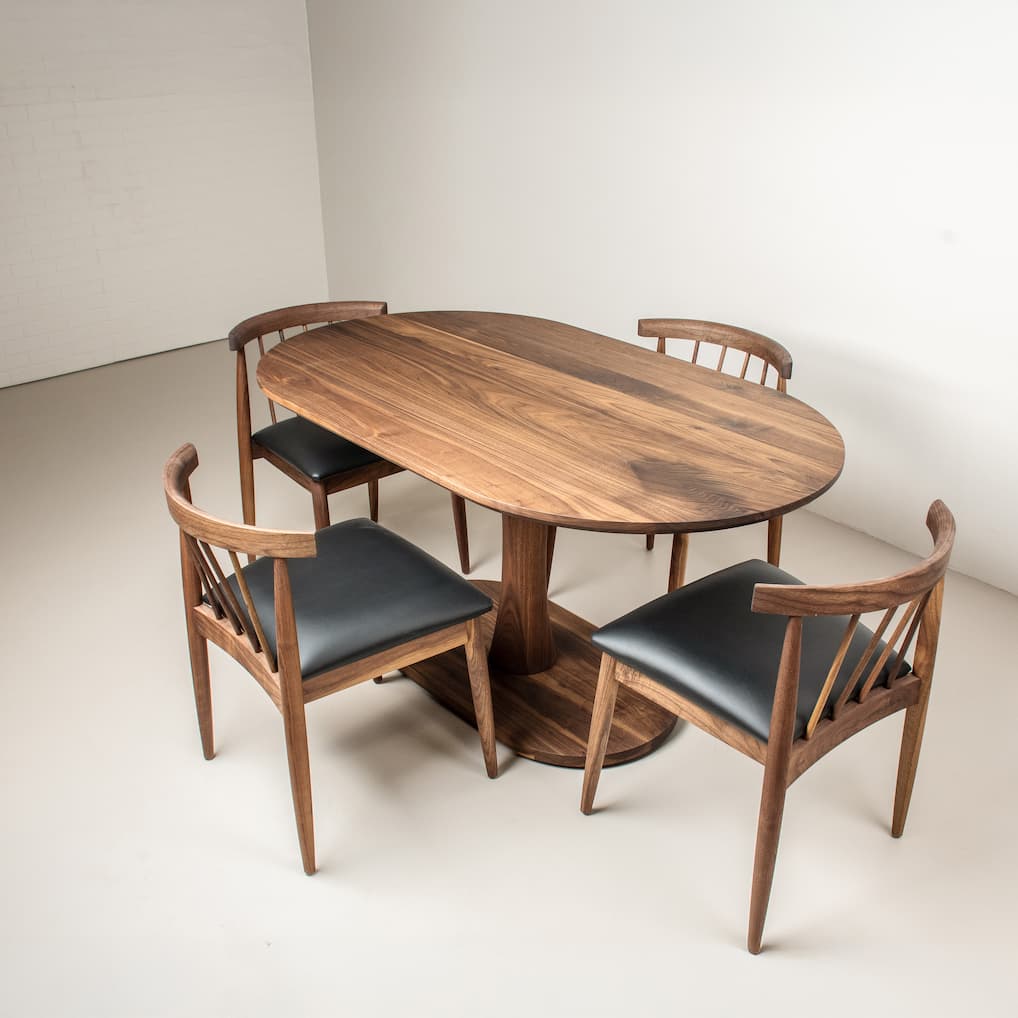 walnut oval table on a pedestal base with spindle chairs