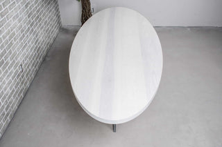 white oval dining table on gunmetal steel pedestal base