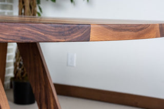 Close up on edge of round walnut dining table. 