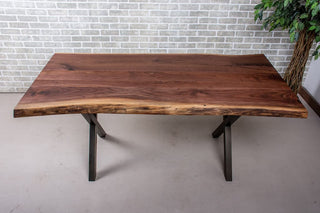 Live edge walnut table on bronze X-shaped steel legs.