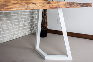 Live edge walnut table on white steel chevron legs.