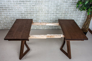 Dark wood extendable dinner table, extended to show hardware.