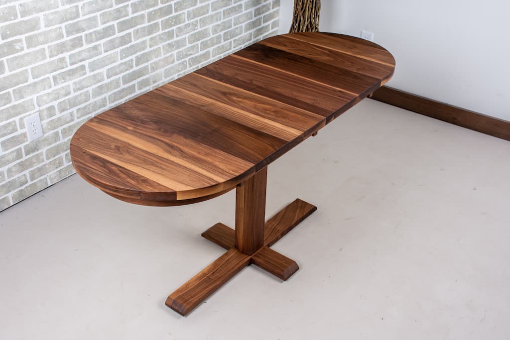 Walnut extendable dining table on a bistro pedestal.