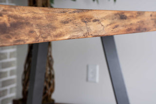 Live edge walnut table on gunmetal chevron shaped legs.