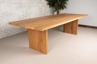 large oak dining table on wood panel legs