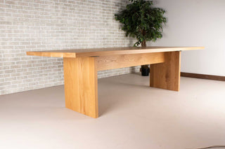 large oak dining table on wood panel legs